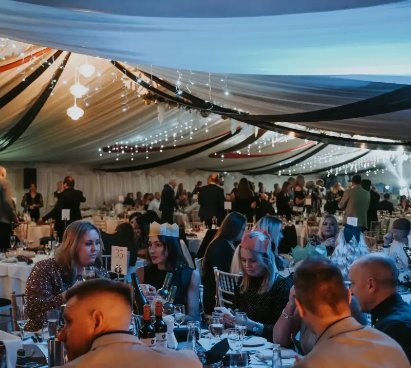 Crowds sitting at tables at a christmas party.