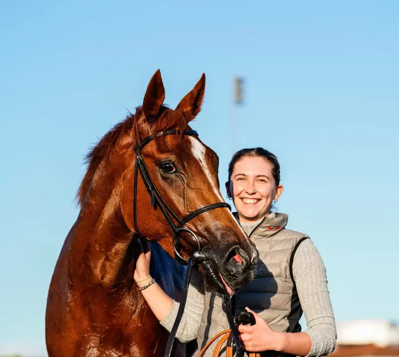 Smiling woman standing next to a horse.