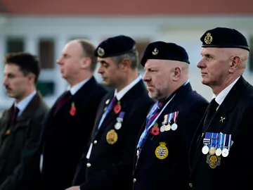 Veterans and service members stand in formation wearing dark suits