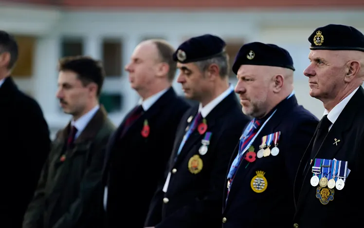 Veterans and service members stand in formation wearing dark suits
