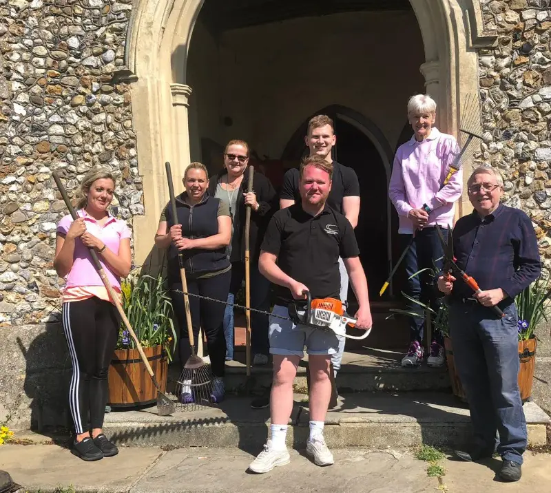 Group of people holding garden tools.